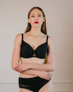 Modelka v čiernej podprsenke NATY a nohavičkách so sieťkovým lemom, ruky prekrížené